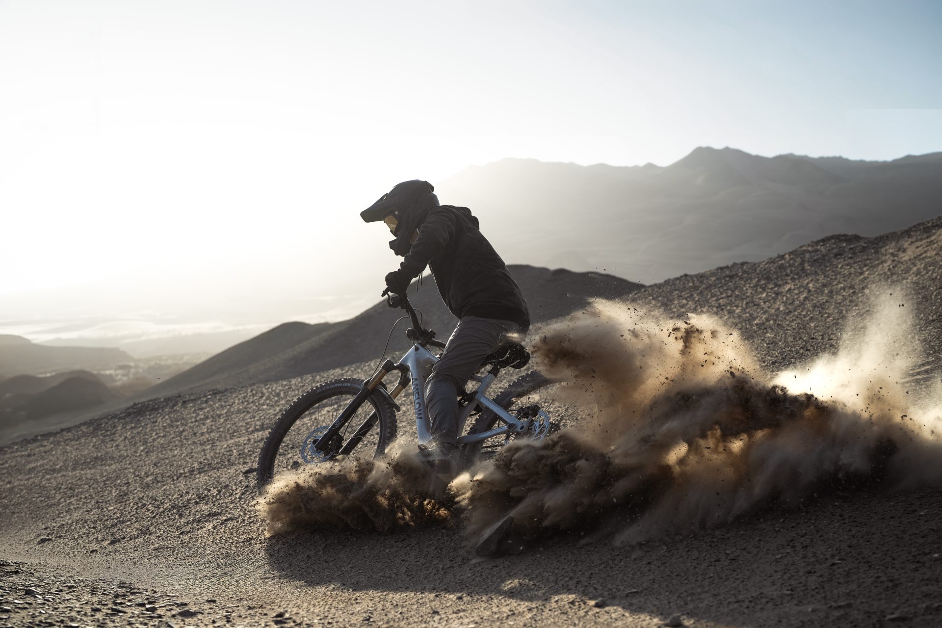 Rider derrapando con una AMFLOW e-MTB completa al atardecer